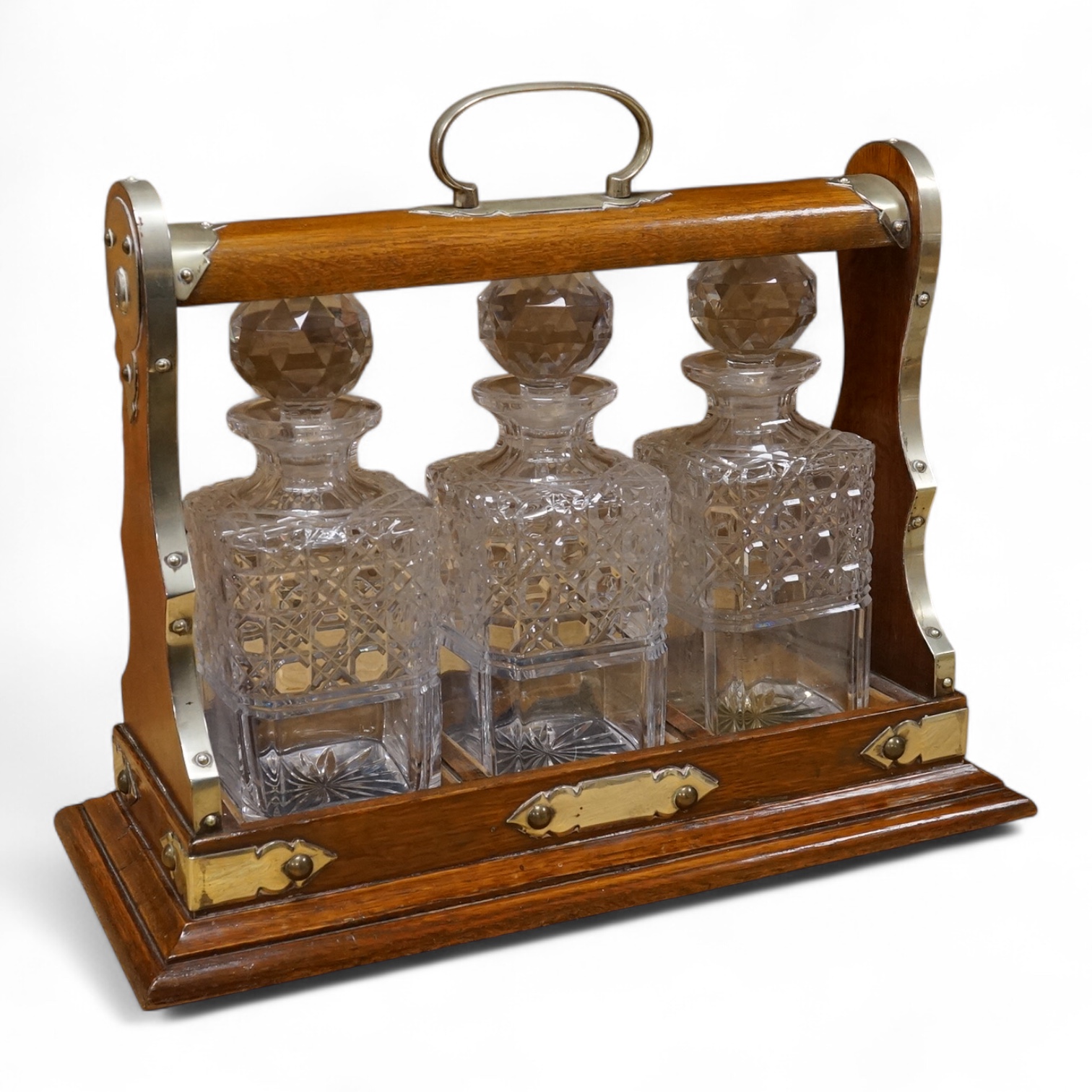 An oak and brass three bottle tantalus, 40cm wide, no key